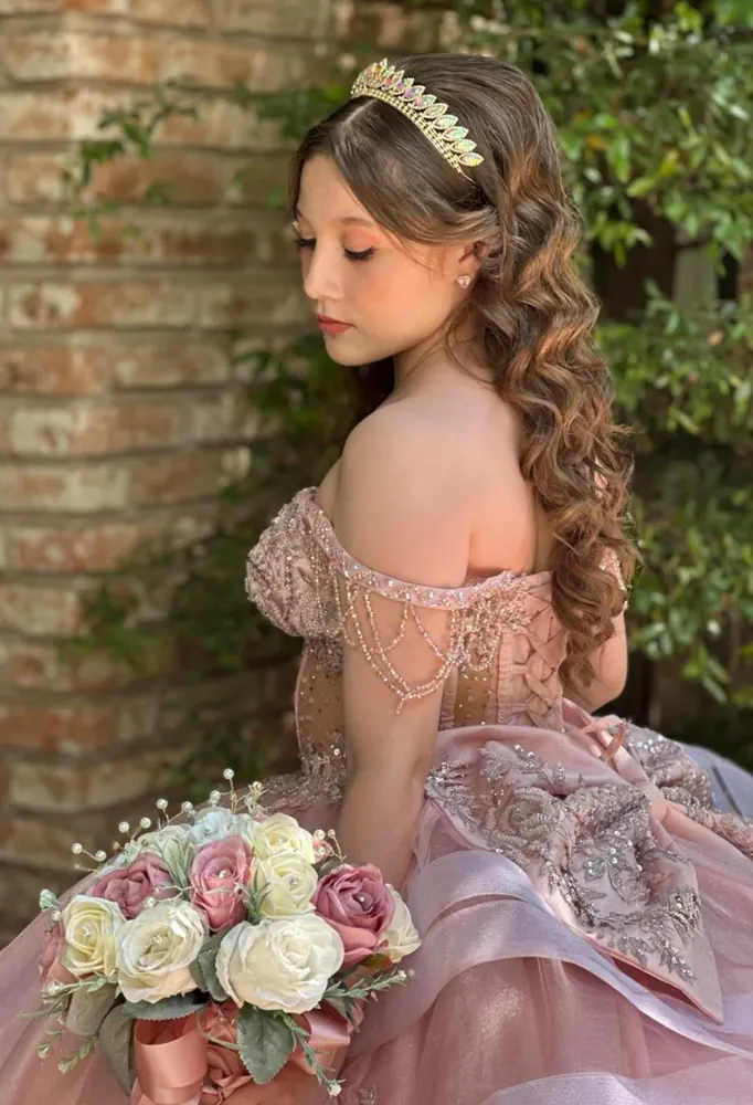 Quinceañera con tiara, maquillaje y peinado de ondas, en el jardín de su evento